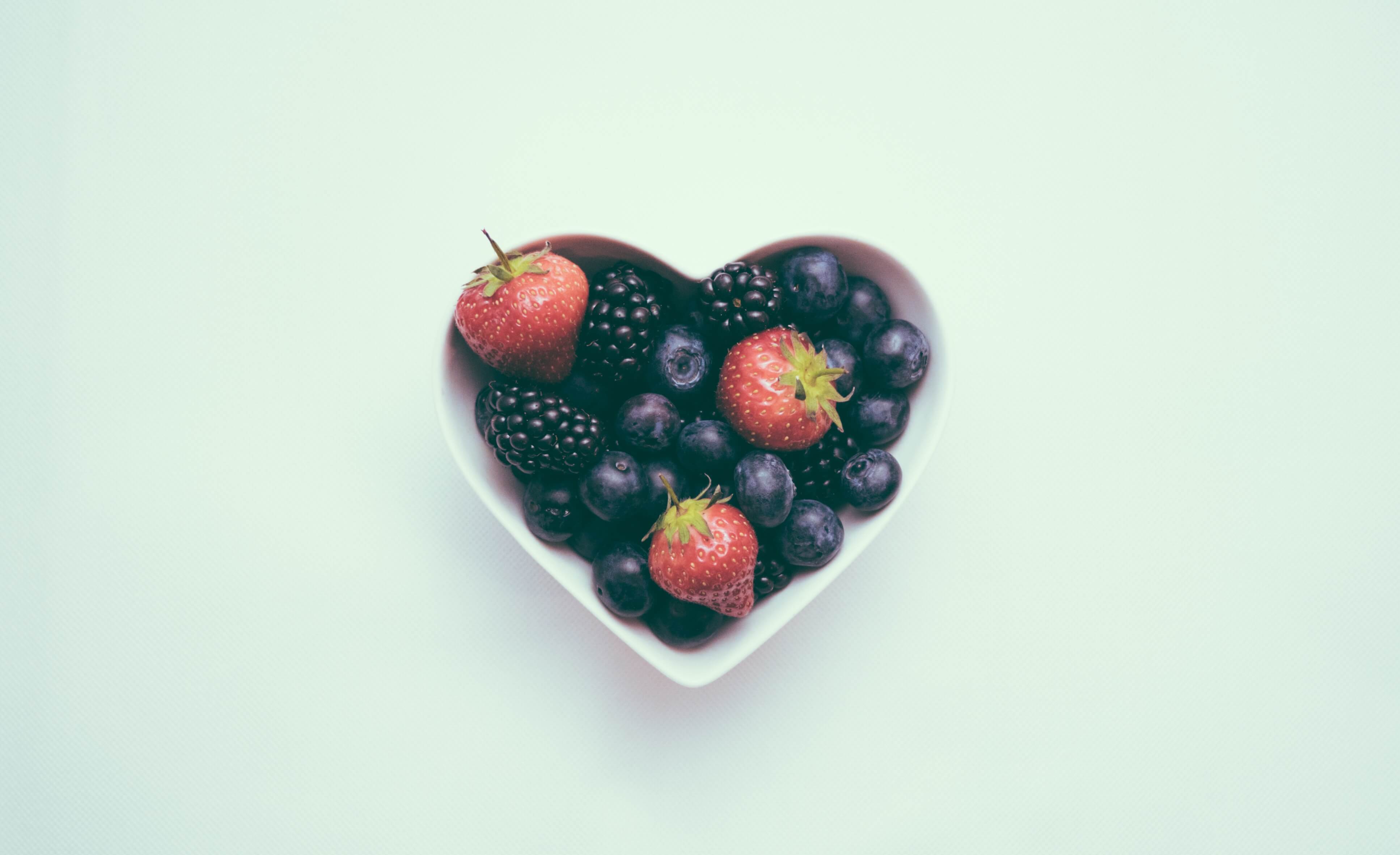 a heart shaped bowl of berries