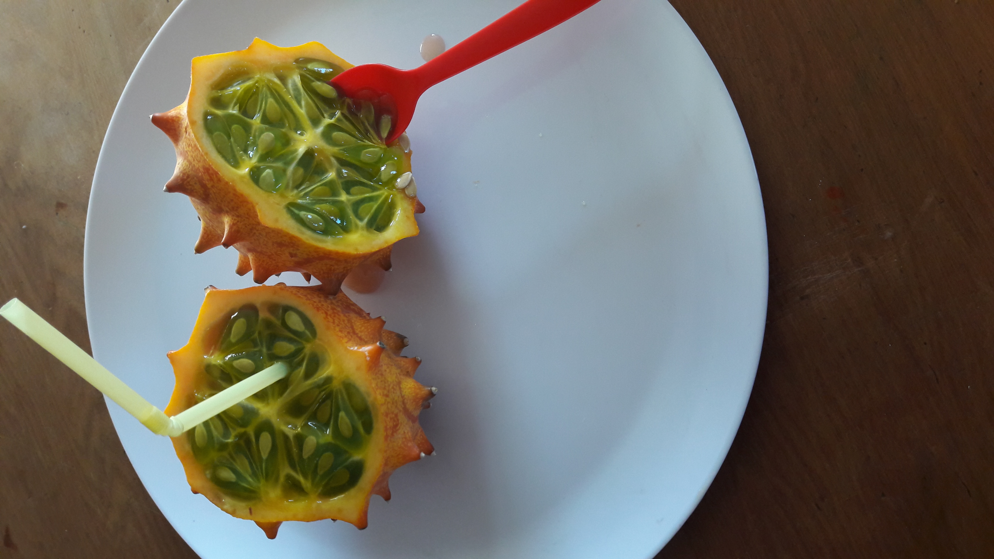 kiwano cut in half with a straw and spoon